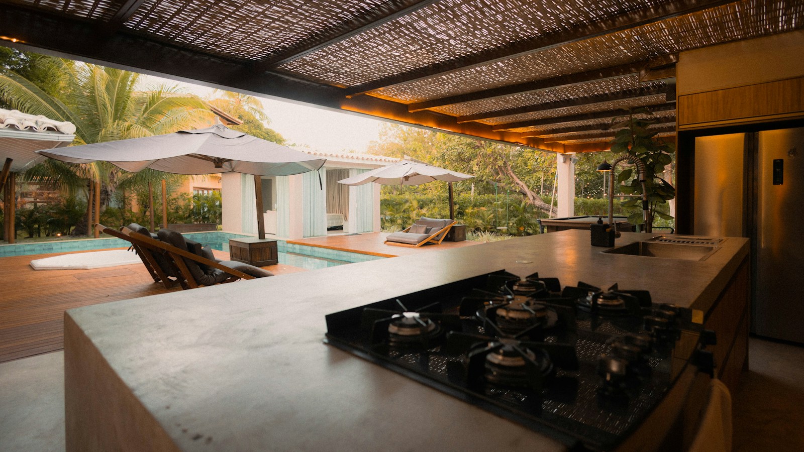 Outdoor kitchen beside a pool in a tropical garden